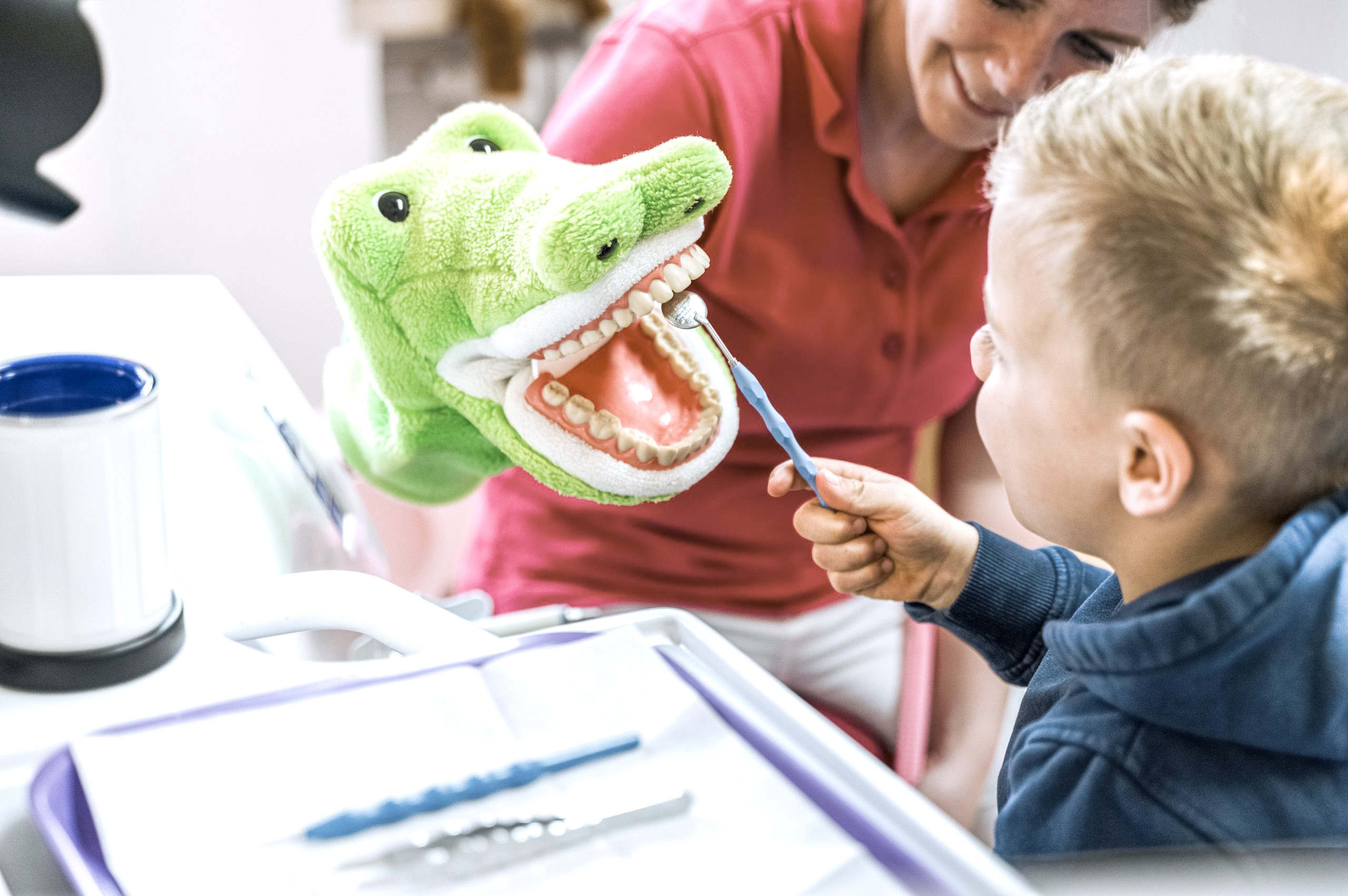 Kind übt spielerisch die Zahnpflege an einem Krokodil-Zahnmodell in der Zahnarztpraxis